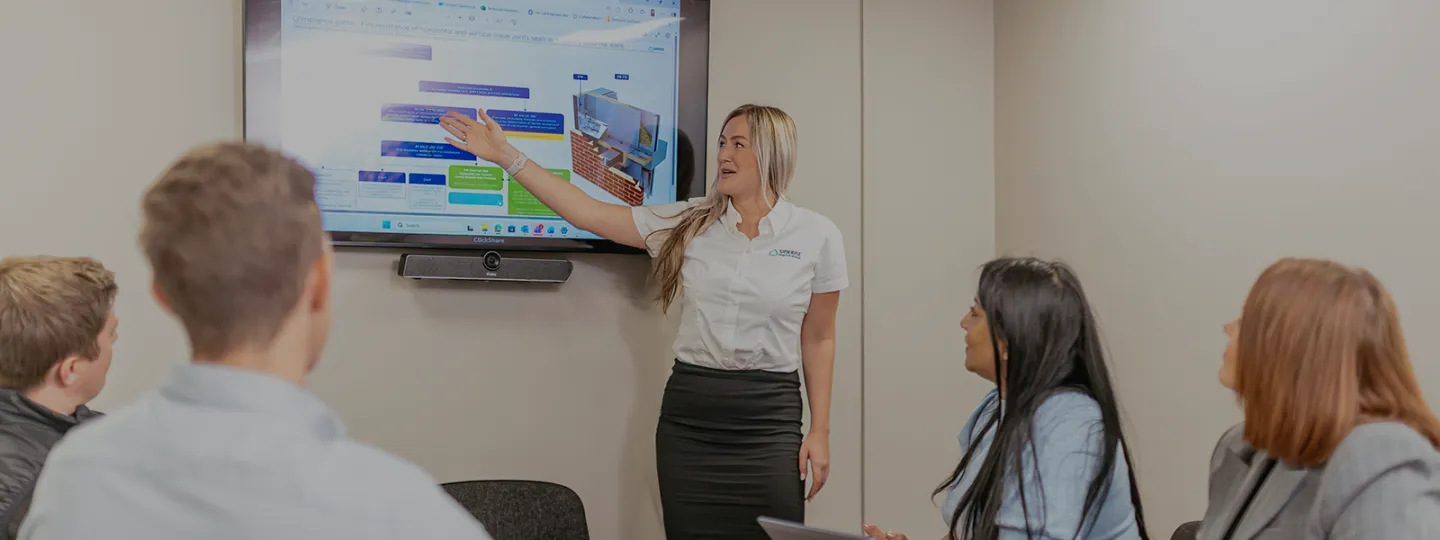Woman pointing to a screen in a class room